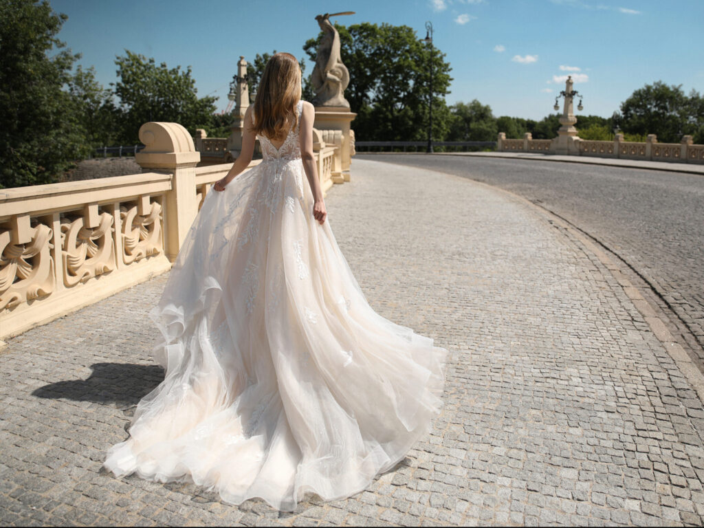 Eine Braut in einem verzierten Brautkleid schreitet über eine Steinbrücke in Weghäusel davon.
